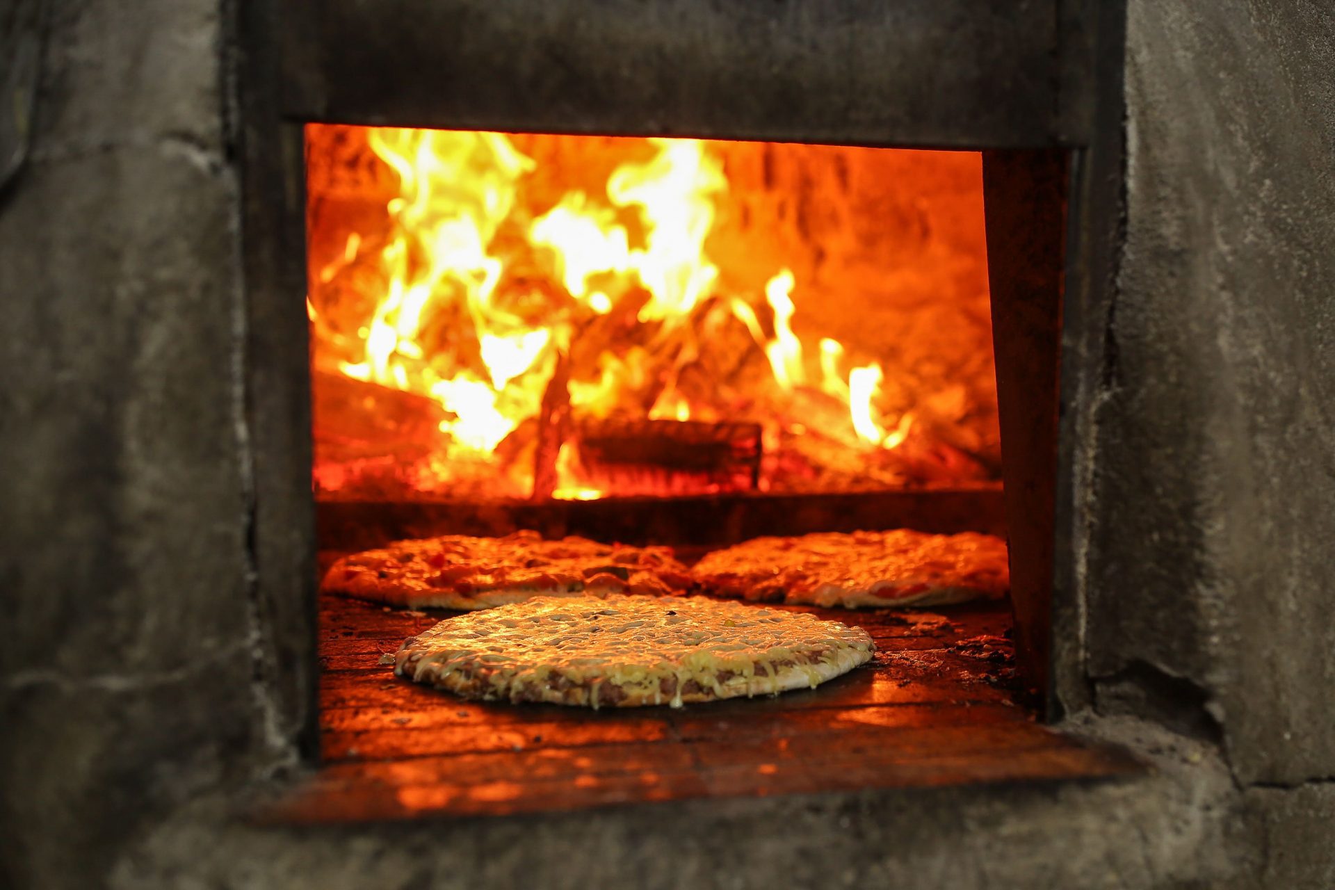 Trío de pizzas en cocción viva dentro de la bóveda del horno