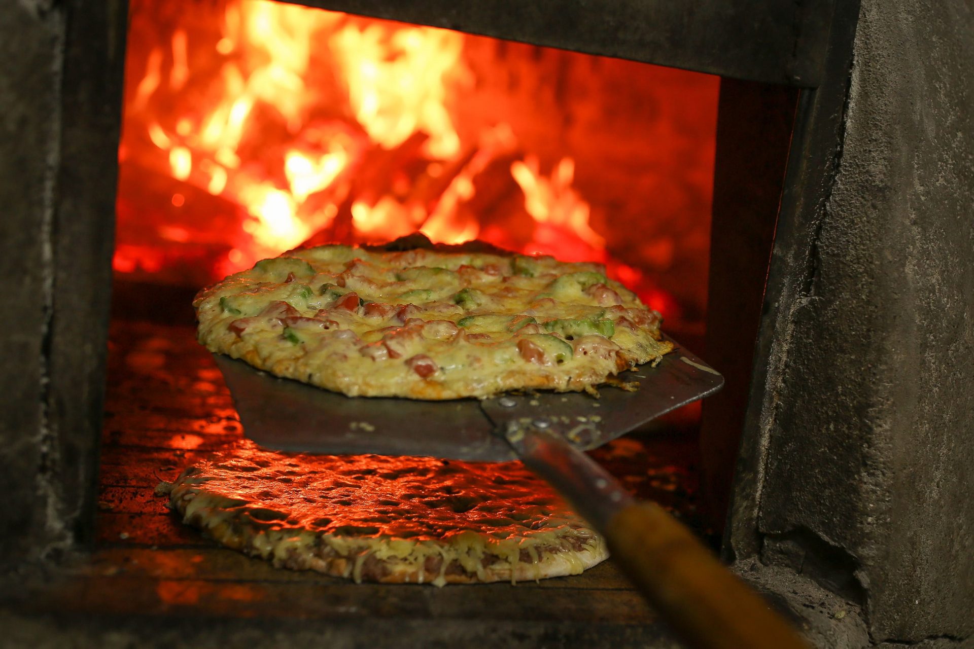 Pala de pizza sacando una preparación al rojo vivo